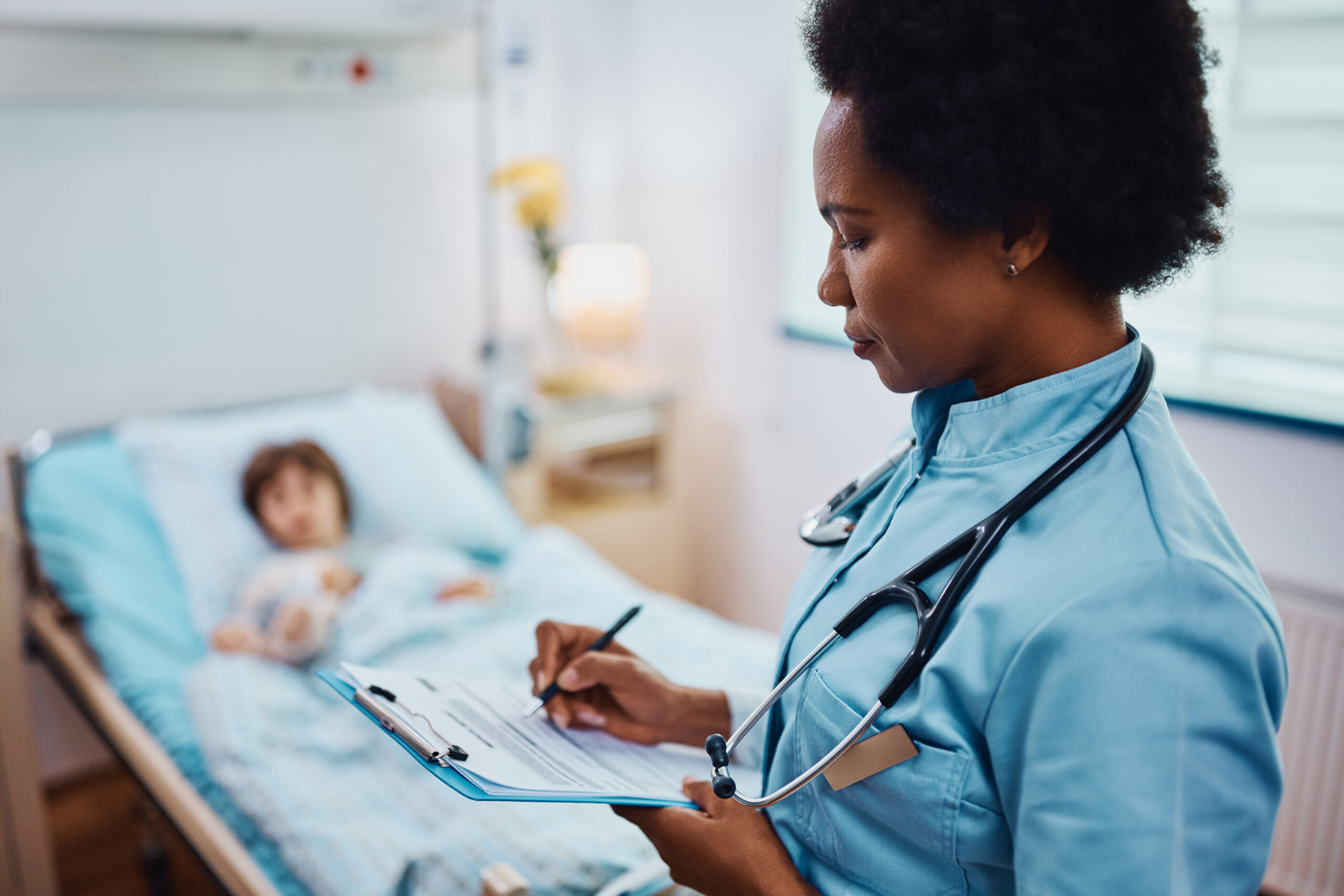 African American nurse filling medical record of hospitalized child