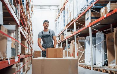 Young,Male,Worker,In,Uniform,Is,In,The,Warehouse,Pushing